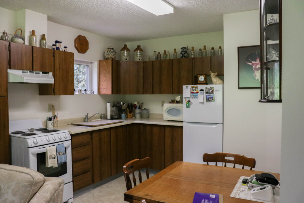 Tenant decorated kitchen.  antique bottles artwork on walls. Microwave and fridge